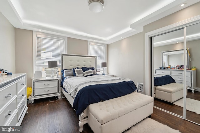 bedroom with dark hardwood / wood-style floors and a raised ceiling