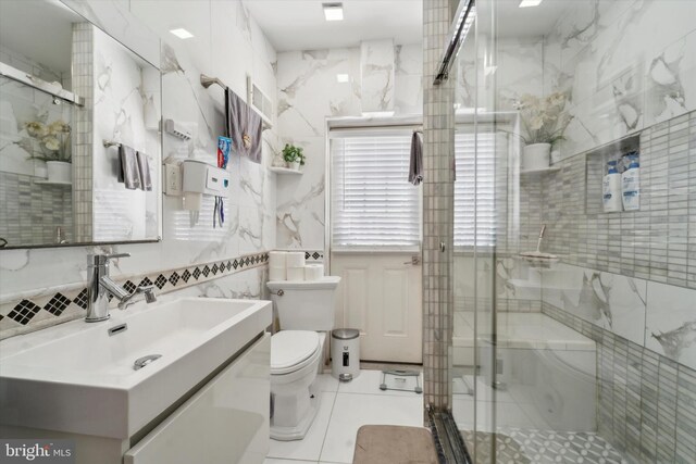 bathroom with a shower with shower door, toilet, tile patterned floors, tile walls, and vanity