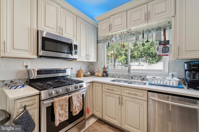 kitchen with decorative backsplash, cream cabinets, stainless steel appliances, and sink