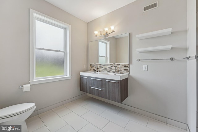 bathroom featuring vanity, backsplash, plenty of natural light, and toilet