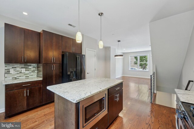 kitchen featuring hardwood / wood-style floors, decorative backsplash, wall chimney range hood, and gas stove