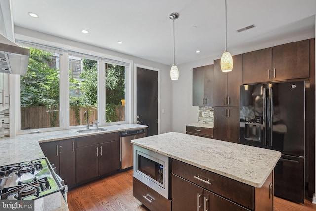 kitchen featuring decorative backsplash, hanging light fixtures, a center island, dark brown cabinetry, and black appliances