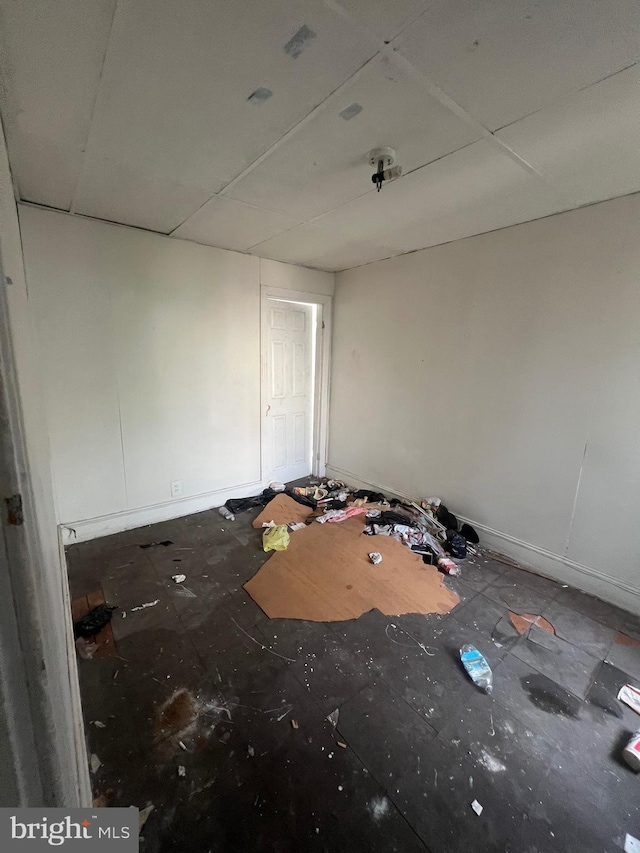 unfurnished bedroom with a paneled ceiling and baseboards