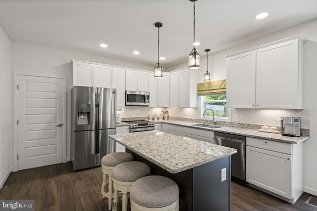 kitchen featuring appliances with stainless steel finishes, decorative light fixtures, dark hardwood / wood-style floors, tasteful backsplash, and sink