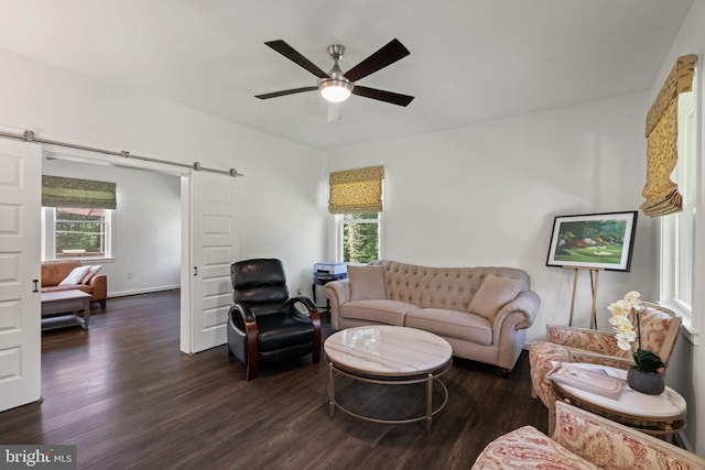 living room with ceiling fan, wood-type flooring, and a barn door