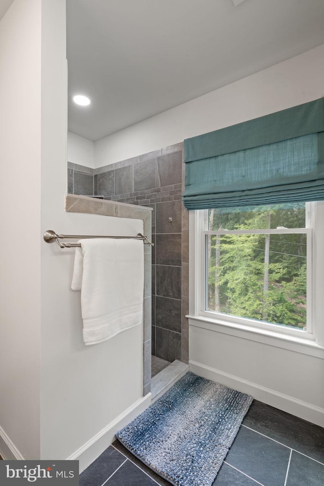 bathroom with tile patterned flooring, tiled shower, and a healthy amount of sunlight