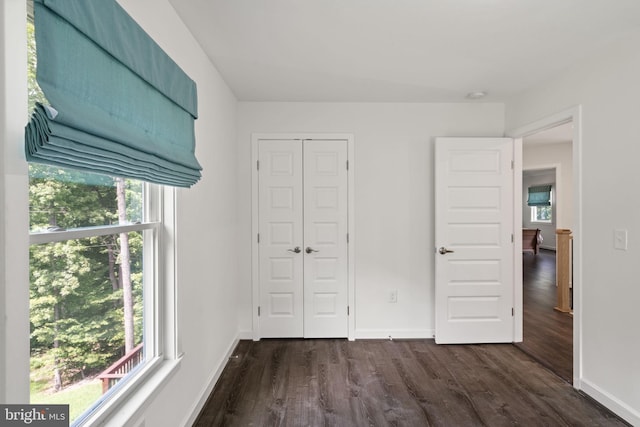 unfurnished bedroom featuring a closet, dark wood-type flooring, and multiple windows