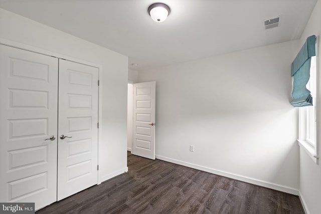 unfurnished bedroom featuring a closet and dark hardwood / wood-style flooring