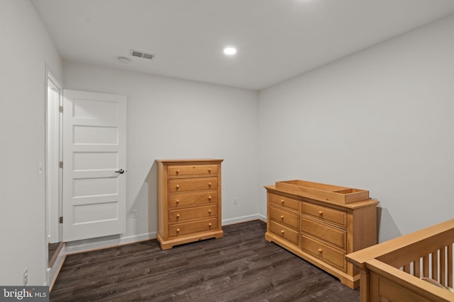 bedroom featuring dark hardwood / wood-style flooring and a crib