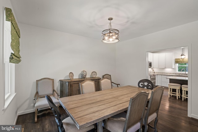 dining room featuring sink, dark wood-type flooring, and a notable chandelier