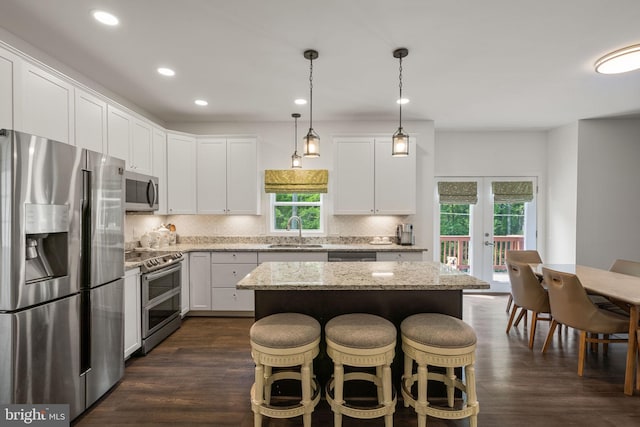 kitchen with appliances with stainless steel finishes, backsplash, sink, a healthy amount of sunlight, and dark wood-type flooring