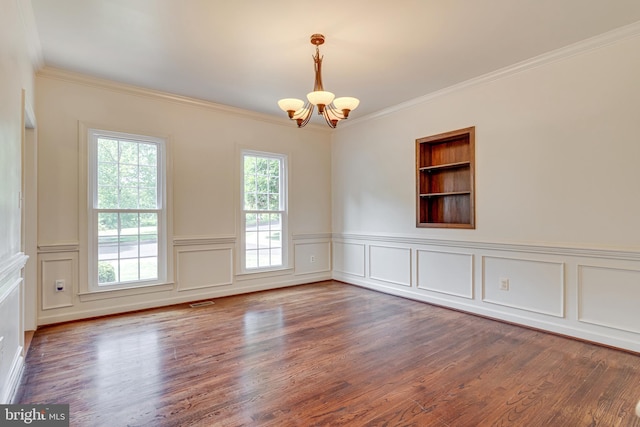 spare room featuring a notable chandelier, hardwood / wood-style floors, crown molding, and built in shelves