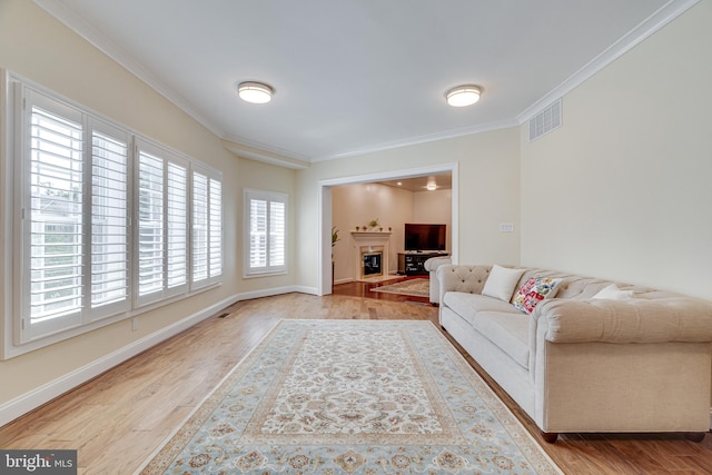 living room with crown molding, a healthy amount of sunlight, and light wood-type flooring