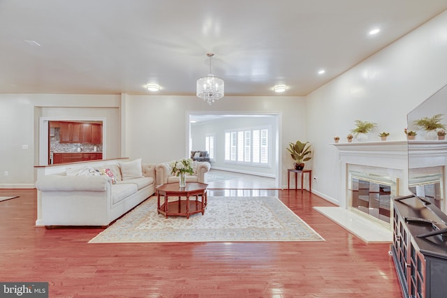 living room with a notable chandelier, wood-type flooring, and a premium fireplace