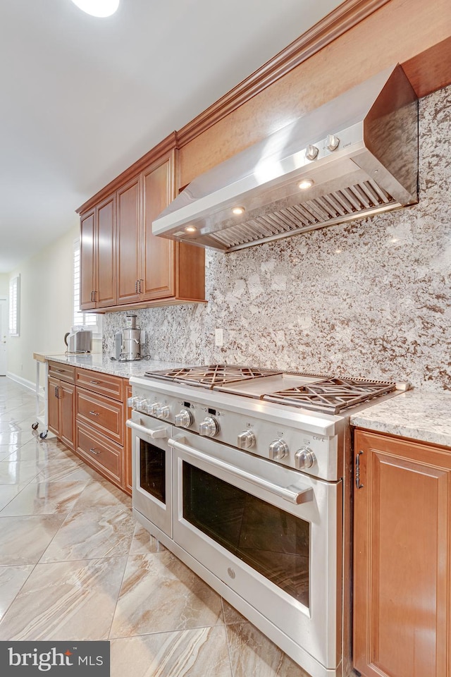 kitchen featuring light tile patterned floors, tasteful backsplash, wall chimney exhaust hood, and double oven range