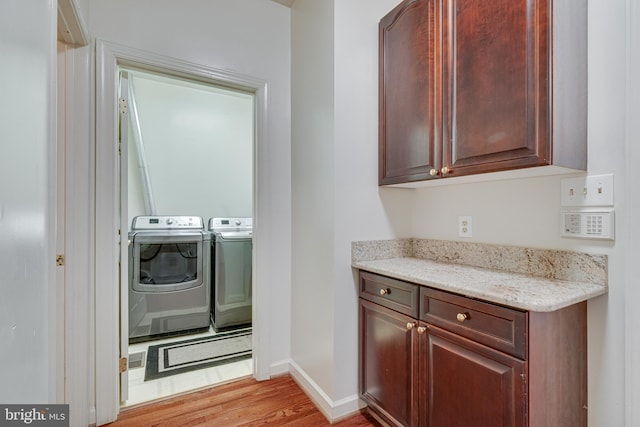 washroom with washing machine and dryer and light hardwood / wood-style floors