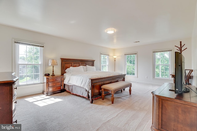 bedroom with light colored carpet and multiple windows