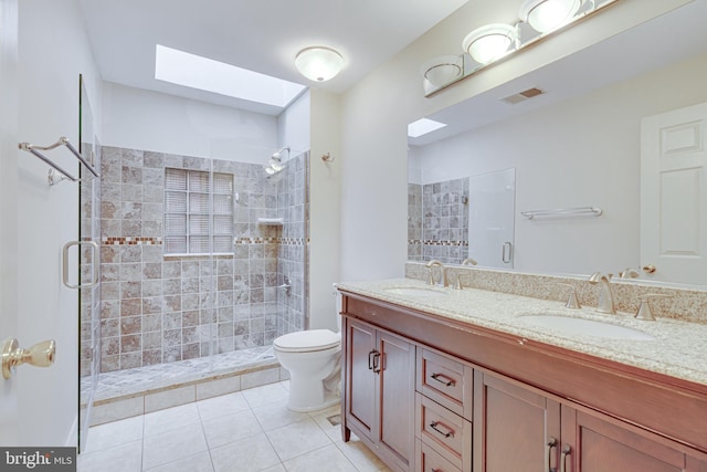 bathroom with a skylight, tile patterned flooring, vanity, toilet, and a shower with door