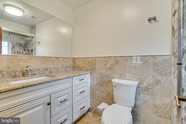 bathroom featuring tile walls, a shower with shower door, tile patterned flooring, vanity, and toilet