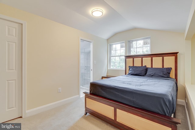 carpeted bedroom with vaulted ceiling and connected bathroom