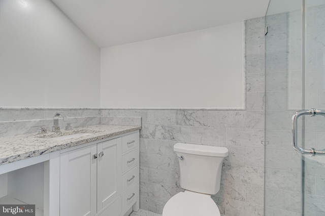 bathroom featuring a shower with door, backsplash, toilet, vanity, and tile walls