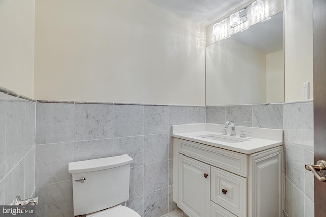 bathroom with tile walls, vanity, and toilet