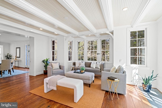 living room featuring baseboards, light wood-type flooring, beam ceiling, and crown molding