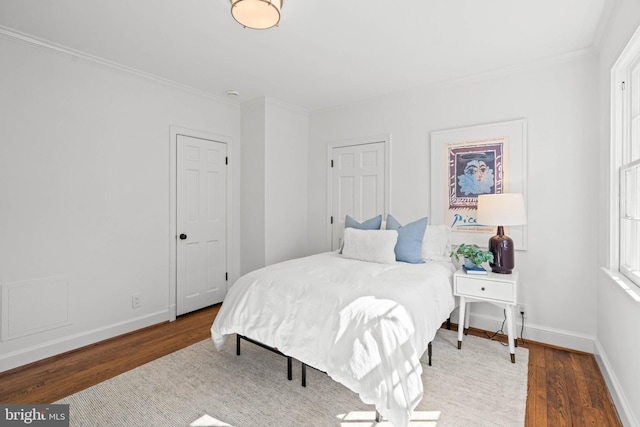 bedroom featuring ornamental molding, wood finished floors, and baseboards