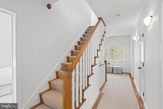 stairway featuring visible vents, baseboards, and ornamental molding