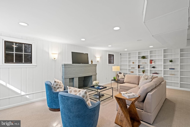 living room featuring a brick fireplace, built in shelves, carpet flooring, and recessed lighting