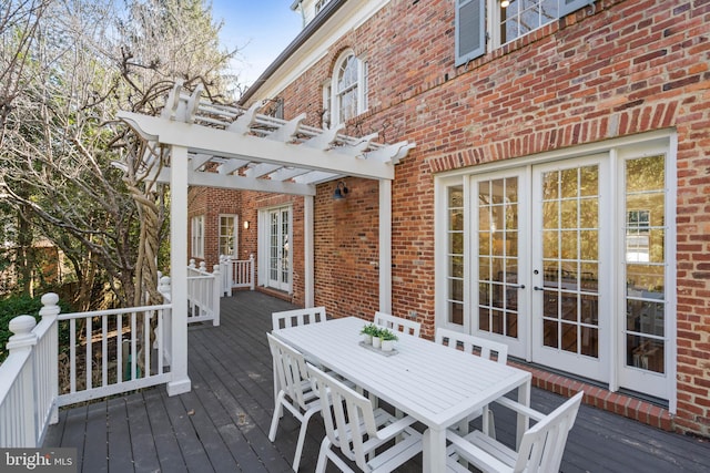 wooden terrace featuring french doors, outdoor dining area, and a pergola