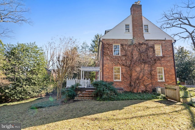 rear view of property featuring central air condition unit, brick siding, a yard, a pergola, and a chimney