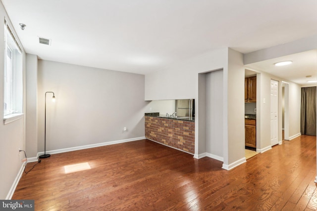 unfurnished living room with baseboards, visible vents, and dark wood finished floors