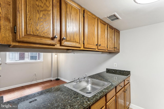 kitchen featuring sink, wood-type flooring, and dark stone counters