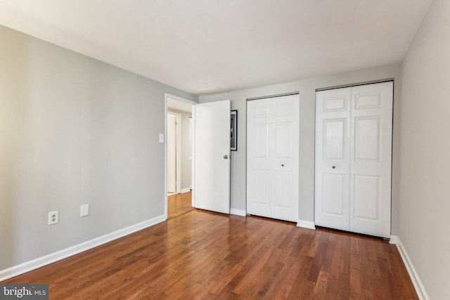 unfurnished bedroom featuring wood-type flooring and multiple closets