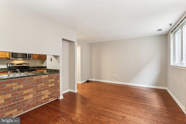 kitchen featuring visible vents, brown cabinetry, appliances with stainless steel finishes, dark wood-style flooring, and a sink