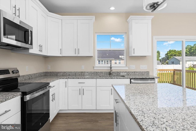 kitchen featuring appliances with stainless steel finishes, dark wood-type flooring, sink, and white cabinets