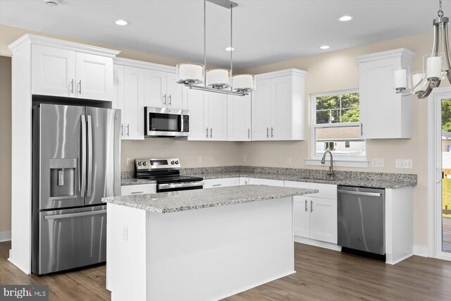 kitchen featuring pendant lighting, appliances with stainless steel finishes, dark hardwood / wood-style floors, and a center island