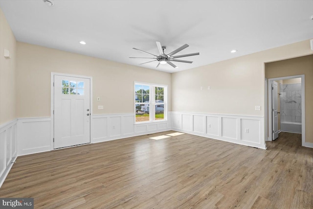 unfurnished living room featuring a wainscoted wall, light wood finished floors, a ceiling fan, and recessed lighting