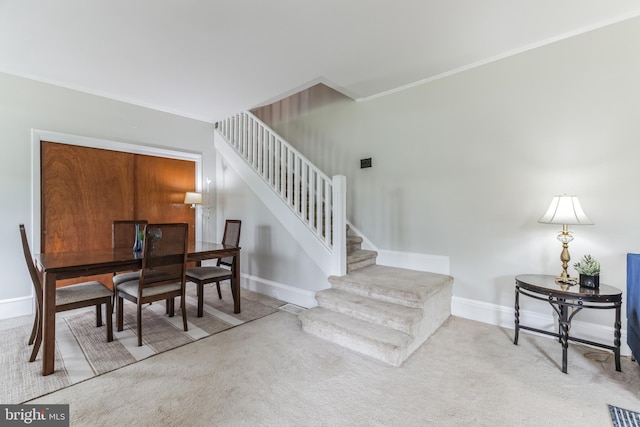 carpeted dining area with crown molding