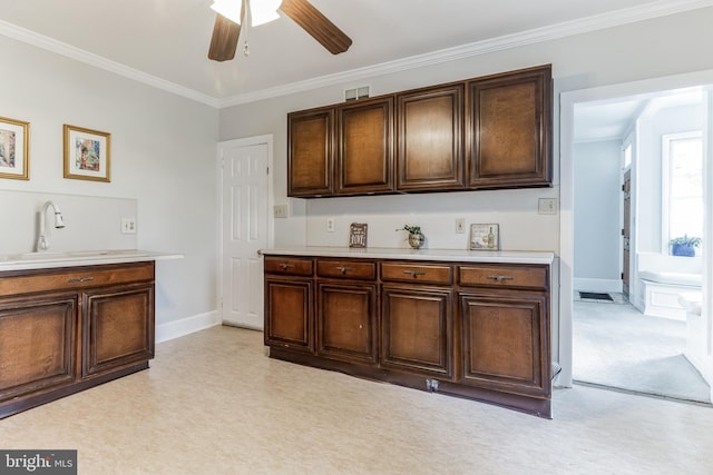 kitchen with dark brown cabinets, ceiling fan, ornamental molding, and light carpet