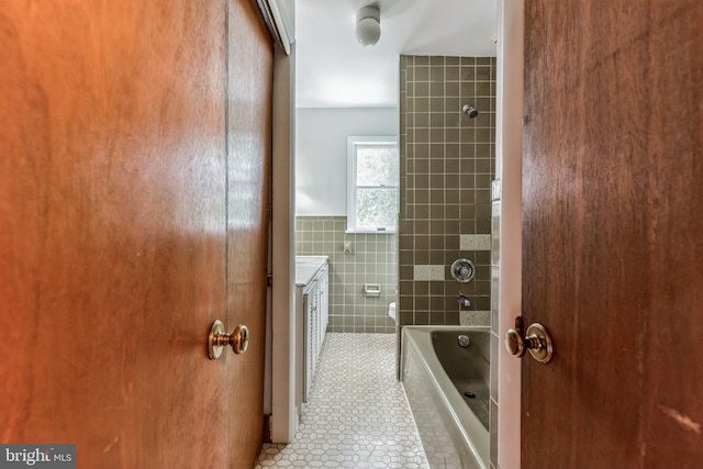 full bathroom featuring toilet, tile walls, tiled shower / bath, tile patterned floors, and vanity