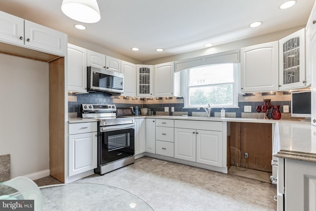 kitchen with white cabinets, range with electric cooktop, tasteful backsplash, and light tile patterned floors