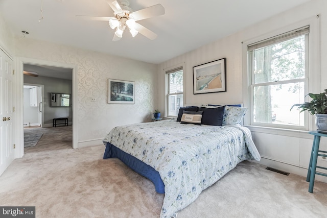 carpeted bedroom with ceiling fan and multiple windows