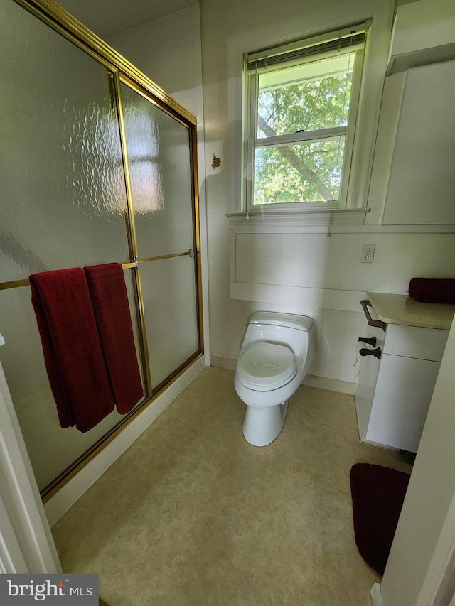 bathroom featuring a shower with door and toilet