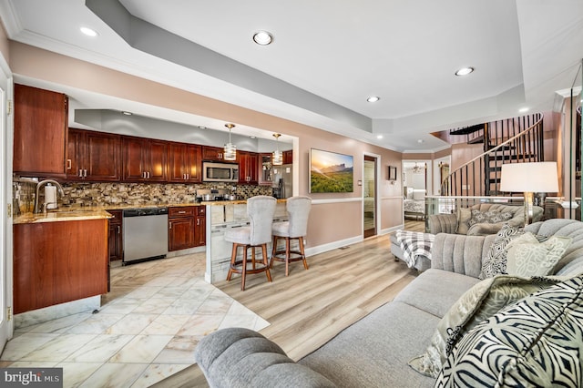 living room with crown molding, sink, and a tray ceiling