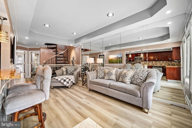 living room with a tray ceiling and light wood-type flooring