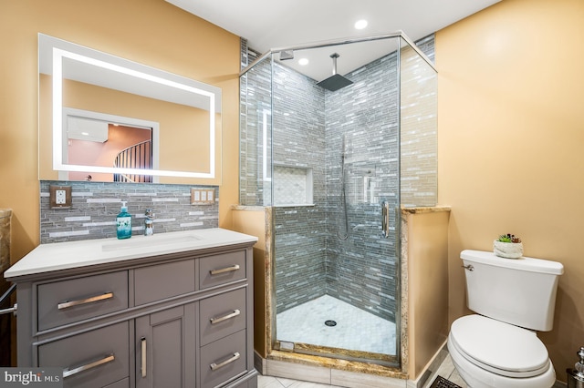 bathroom with vanity, backsplash, a shower with door, and toilet