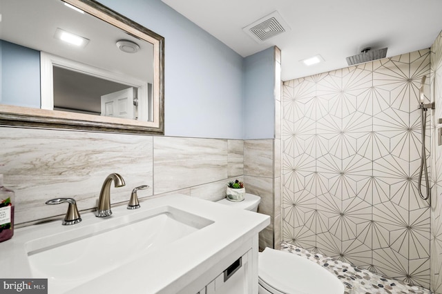 bathroom with tile walls, vanity, a shower, and toilet