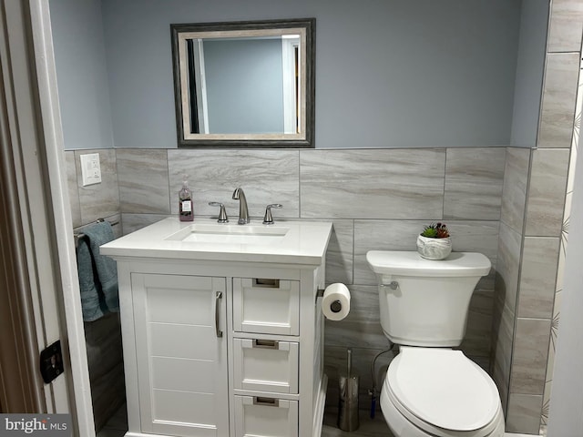 bathroom featuring vanity, tile walls, and toilet